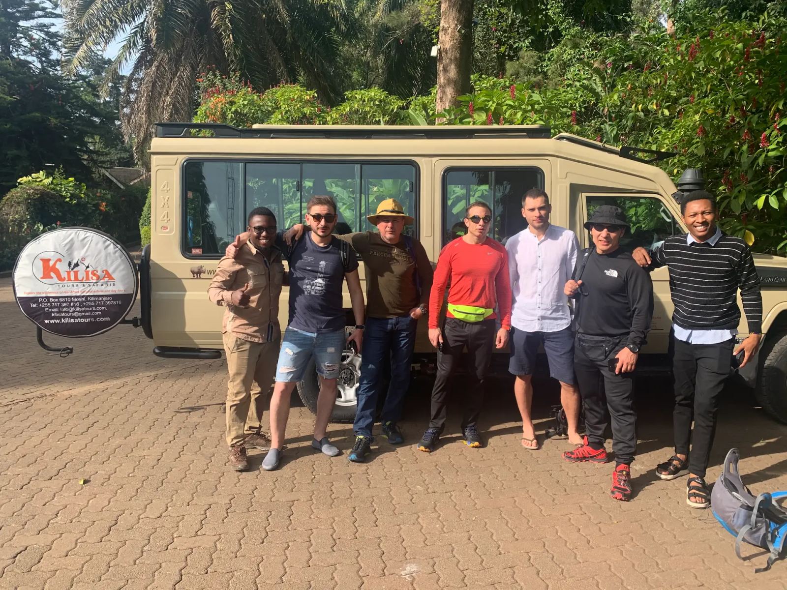 Group of guests and guides standing in front of a Kilisa Tours safari Land Cruiser