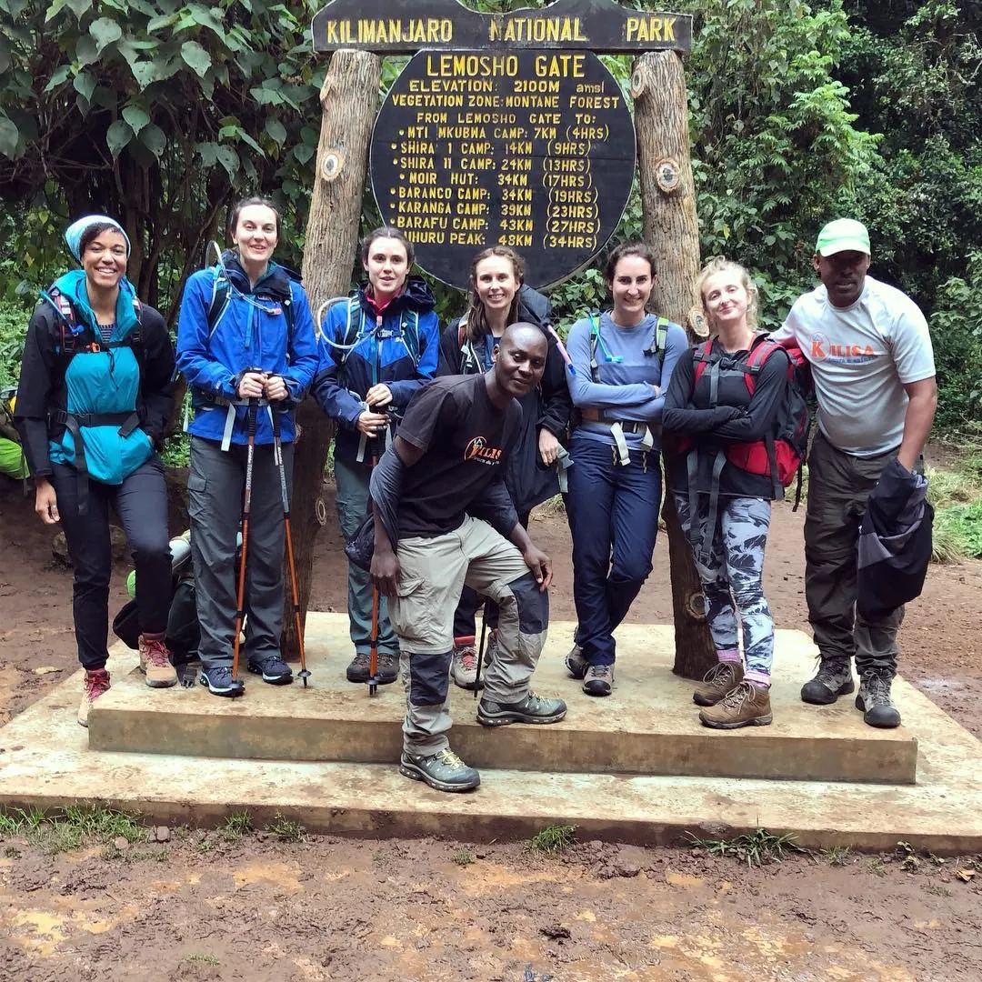 Trekking group and guides at the Lemosho Gate sign, 2,100 m, start of the Lemosho route on Kilimanjaro
